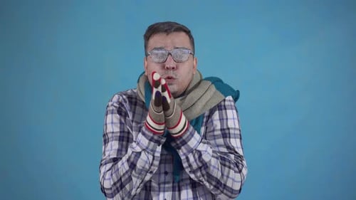 Homme gelé couvert de givre et portant des gants et un foulard sur fond bleu