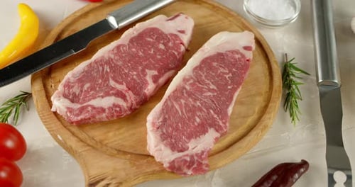 Raw Steak on Wooden Cutting Board with Knife