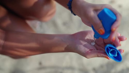 4K Asiatin in Bademode trägt am Strand Sonnenschutzlotion auf ihr Gesicht auf