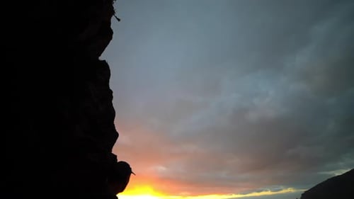 Person on Cliff Overlooking the Ocean at Sunset