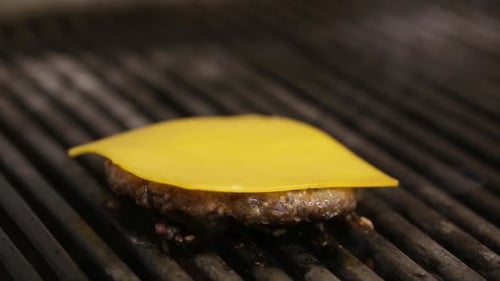 Close up Of Cook Flipping Burger Meat on A Kitchen Grill and Adding Cheese