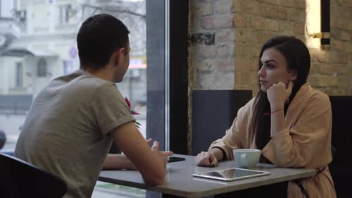 Portrait of Young Caucasian Girlfriend Sitting in Cafe with Boyfriend Talking