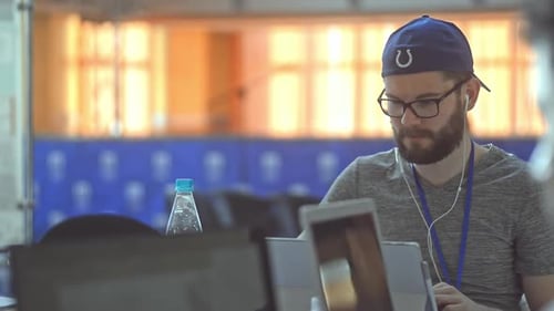 Hipster Man Wearing Pass and Headphones Testing Work on New Device Laptop Computer or Tablet Lrrl