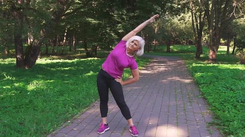 Retired woman doing warm-up before training in the park.