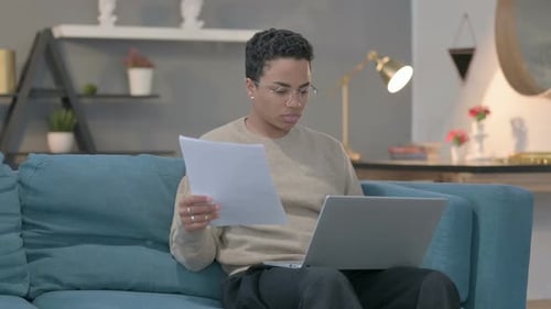 Adult Sits on Couch Working with Laptop