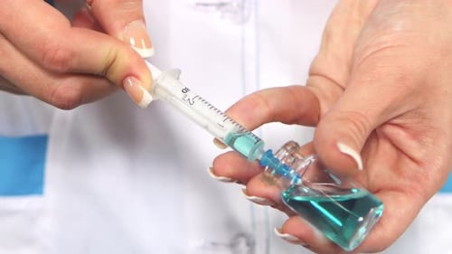 Healthcare Worker Filling Syringe with Teal Solution
