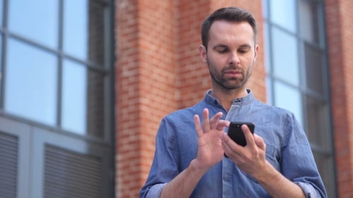 Man Using Smartphone While Standing Outside Office, Browsing Online