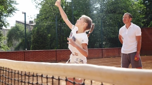 Girl Practices Tennis with Coach on Outdoor Court