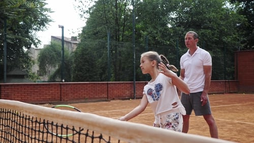 Girl Learns Tennis with Coach on Outdoor Court
