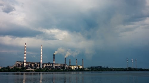 Rauch aus den Rohren eines Kraftwerks am Ufer eines Flusses