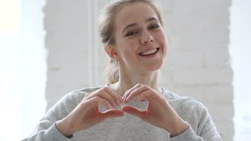Smiling Woman Makes Heart Shape With Hands