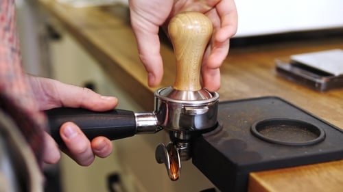 View of Baristas Hands Tamping Fresh Ground Coffee and Taking It Away