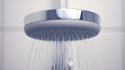 Shower Head Dispensing Water in Bathroom Close Up