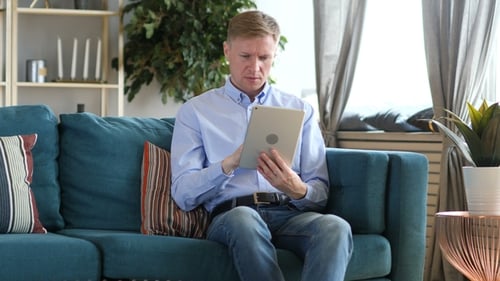 Man Using Tablet While Sitting on Couch