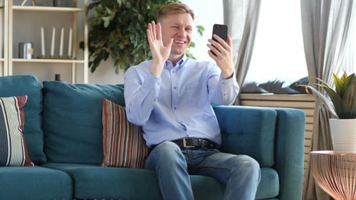 Young Man Video Chats on Smartphone at Home