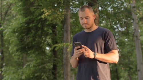 Man Using Phone in Sunny Green Urban Park