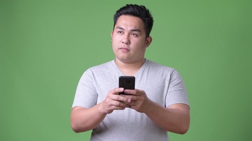 Young Adult Holding Smartphone Against Green Screen