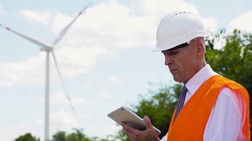 Energy Engineer Working on Digital Tablet Agains Windmills Farm