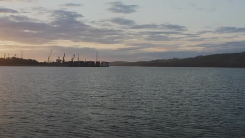 Silhouetten von Frachtkranen, die am frühen Morgen in der Morgendämmerung im Hafen arbeiten