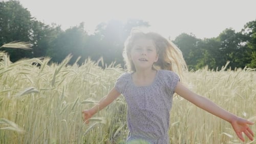 Happy Girl Running Through Wheat Field in Summer