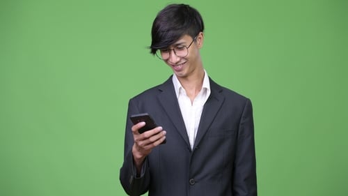 Young Adult Uses Smartphone in Front of Green Screen