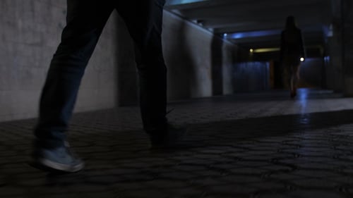 Person Walking Through Dark Urban Underpass at Night