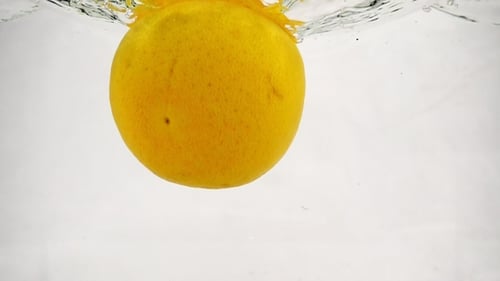 A Whole Grapefruit Falls Into the Water with Bubbles