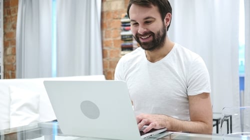 Man Using Laptop and Waving Indoors