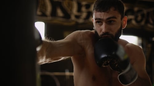 Strong Boxer Training with Heavy Bag in Urban Gym