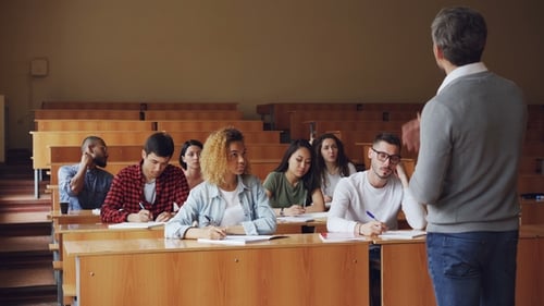 Tutor Is Talking To Students Sitting at Desks in Spacious College Lecture Hall