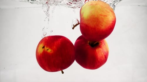 Video of Red Apple Falling Into Water with Bubbles. Fruits on Isolated White Background.