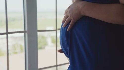Vue de Caresser avec les mains Womb dans le ventre à la fenêtre
