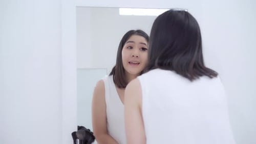 Woman Applying Makeup in Mirror in Bright White Room