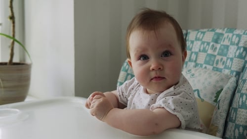 Adorable Infant Sitting in High Chair Looking Forward