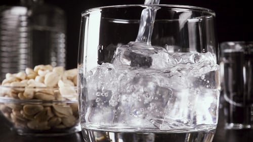 Sparkling Water Being Poured into Glass Over Ice
