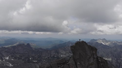 A Man Stands on Top of a Mountain