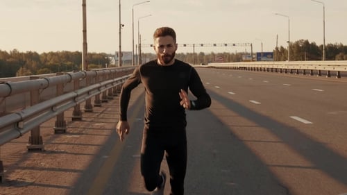 Man Running Toward Camera on Highway at Sunrise