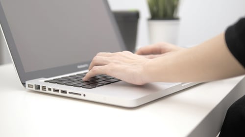 Typing on Silver Laptop Keyboard at Desk