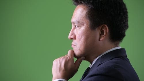 Reifer japanischer Geschäftsmann vor grünem Hintergrund