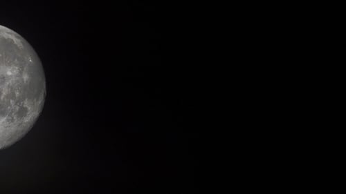 of an Extreme Large Full Moon As It Rises in the Bight Sky with Black Clouds in Its Foreground