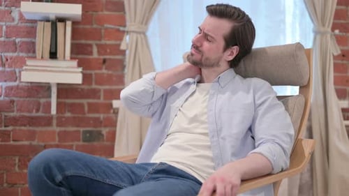 Young Man Having Neck Pain While Sitting on Sofa