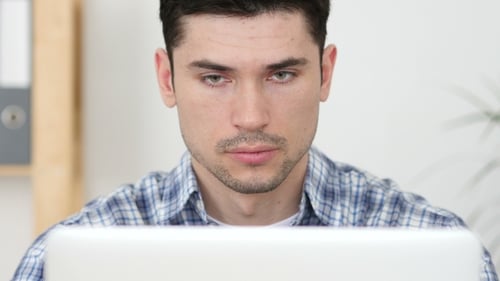 Focused Young Adult Works on Laptop in Office