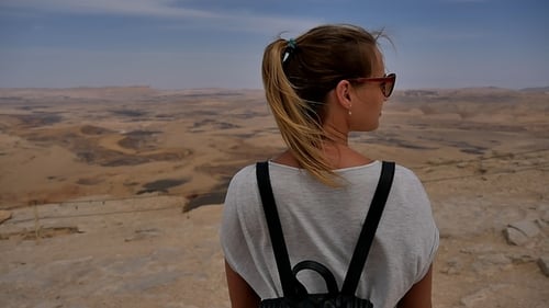 Junge Frau mit Sonnenbrille genießt den Blick auf die Steinwüste am Rande der Klippe