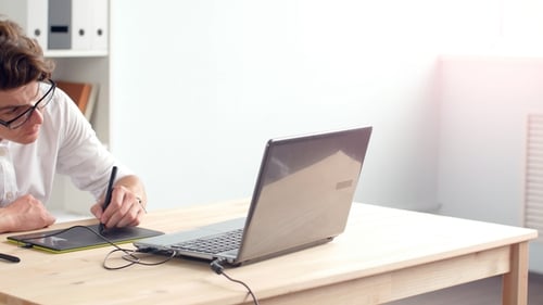 Young Adult Using Graphic Tablet at Desk