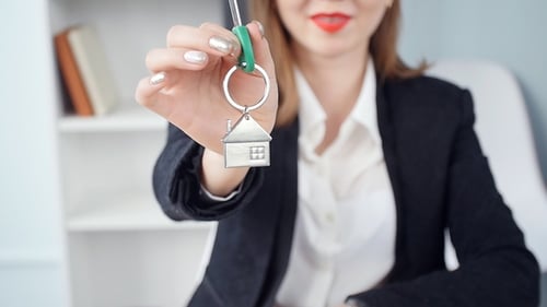 Woman Holds Out Keys with House Keychain
