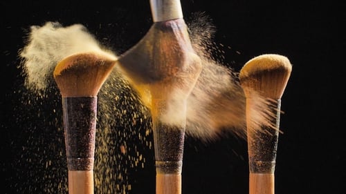 Pinceaux cosmétiques avec poudre cosmétique dorée sur fond noir