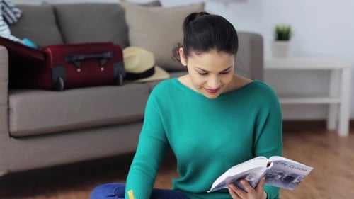Woman with City Guide Preparing for Travel at Home 1