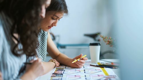 Junge Architektinnen diskutieren mit Blueprint im Büro