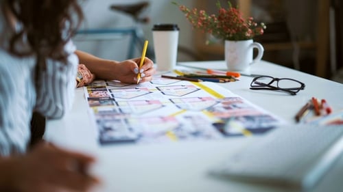 Two Woman Architects Discussing Plan Together At Desk With Blueprints