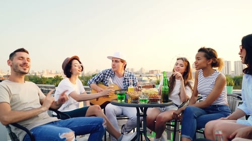 Friends Enjoying Rooftop Party with Music and Drinks